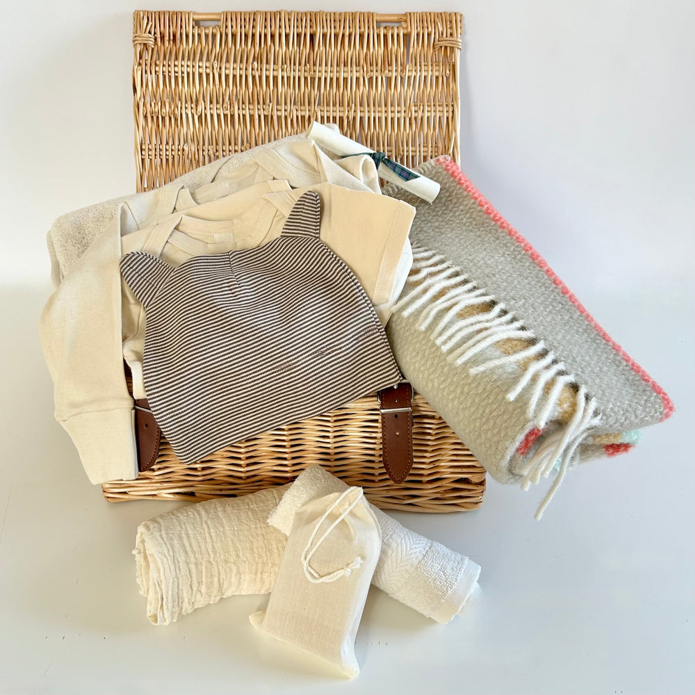 The St Andrews Hamper Company exclusive new baby wicker hamper filled with eco and organic clothes and accessories including a pure new wool baby blanket in coastal stripes.