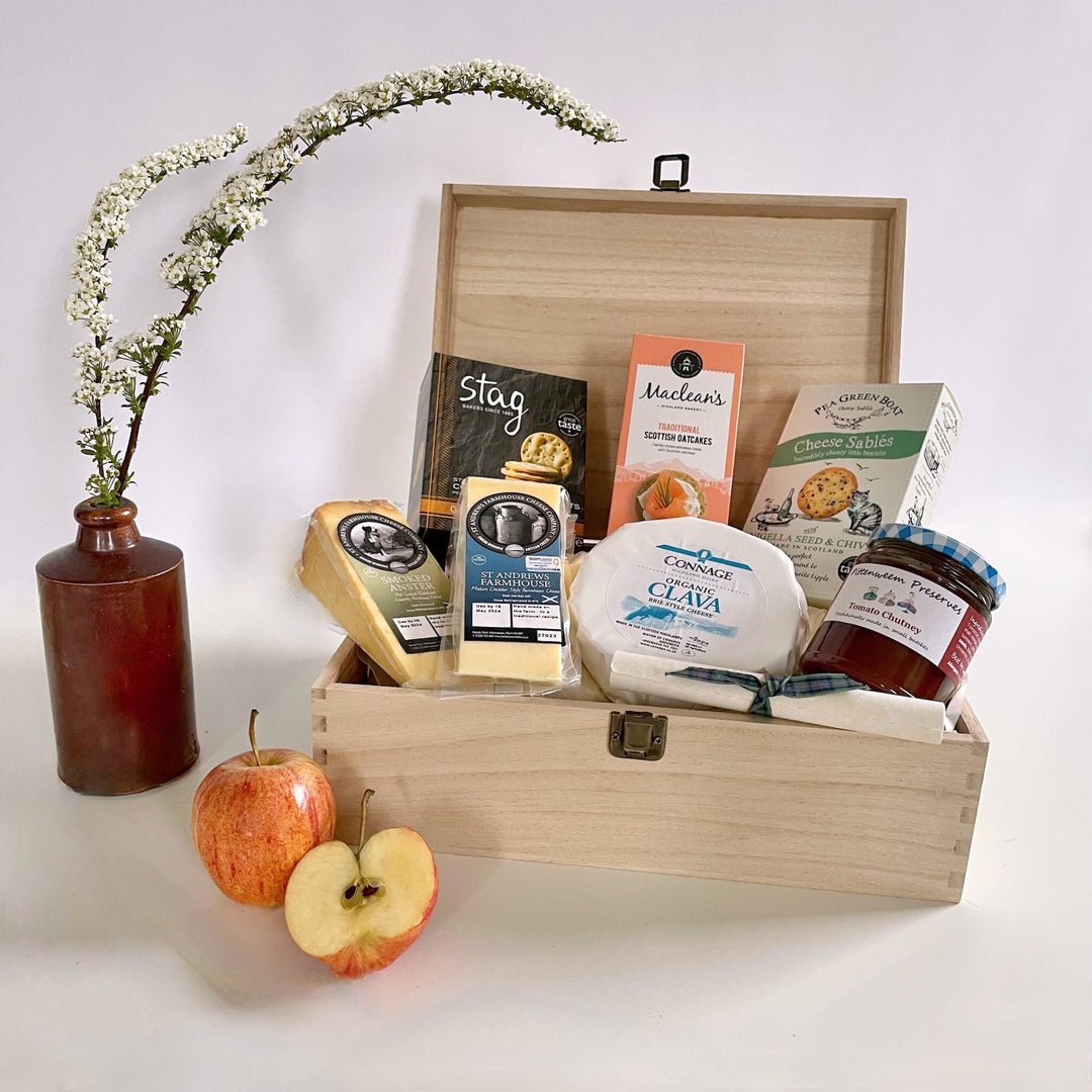 The St Andrews Hamper Company Cheese Lover's Tuck Box, featuring three cheeses, homestyle chutney plus oatcakes and cheesy nibbles. presented in a keepsake wooden box.