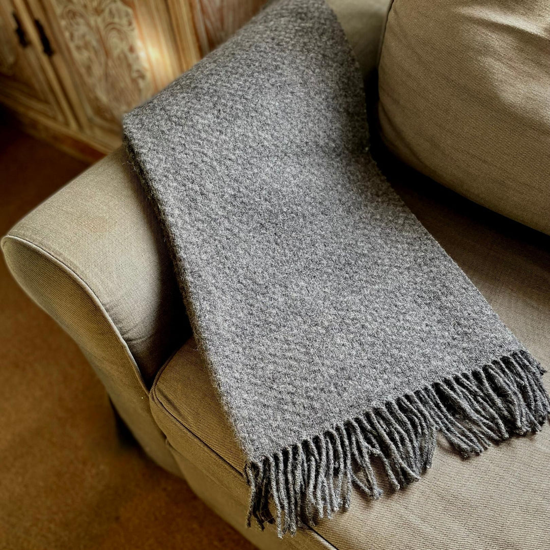 St Andrews Hamper Company luxurious pure new wool armchair throw in slate grey with contemporary wafer pattern and self coloured twisted tassel fringing. Perfect as a soft and cosy shoulder wrap for snuggling into, as a stylish knee rug or the finishing touch to a bed, sofa or armchair.