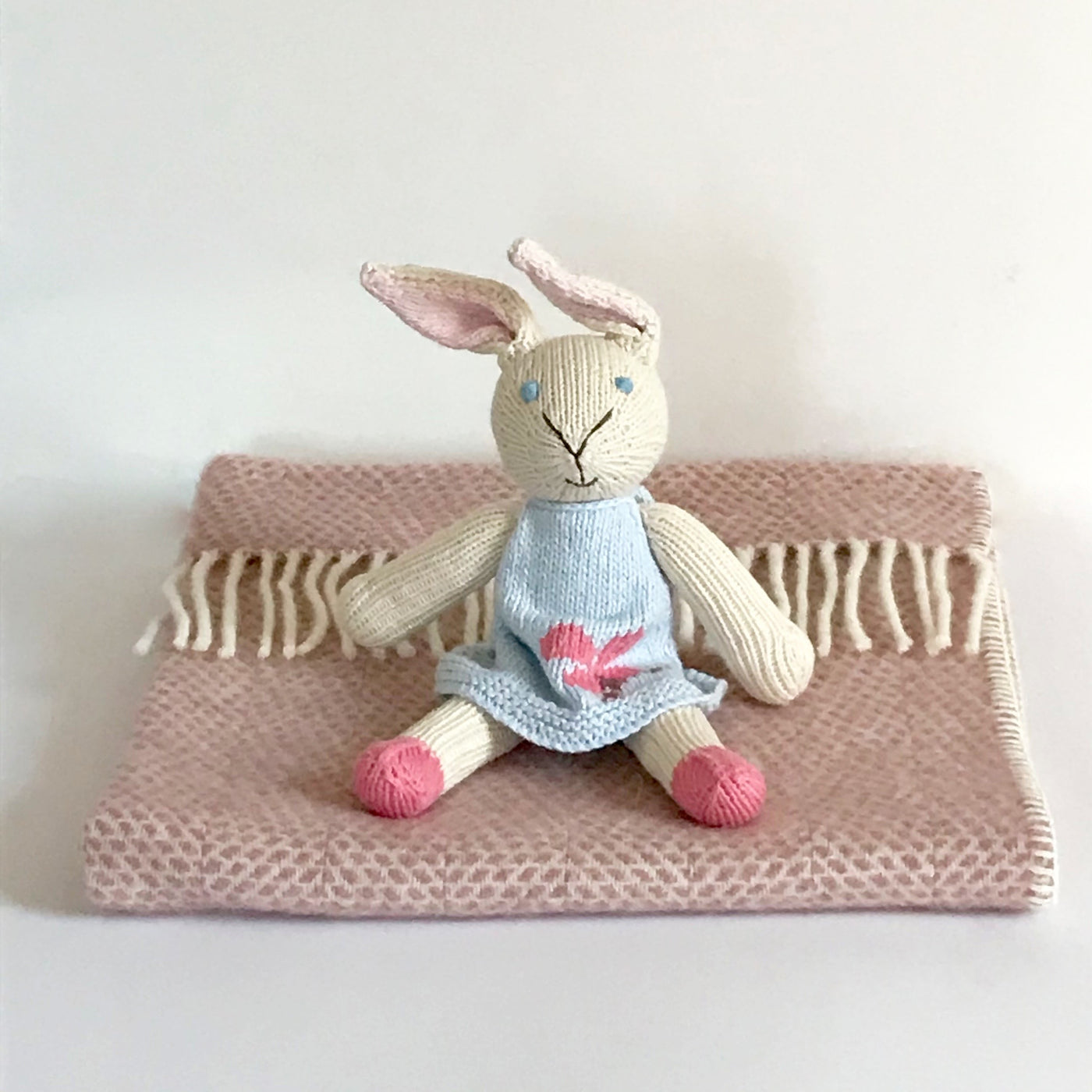 Rory & Ruby pure new wool baby blanket in dusky pink with organic cotton hand knitted rabbit soft toy with a blue dress.
