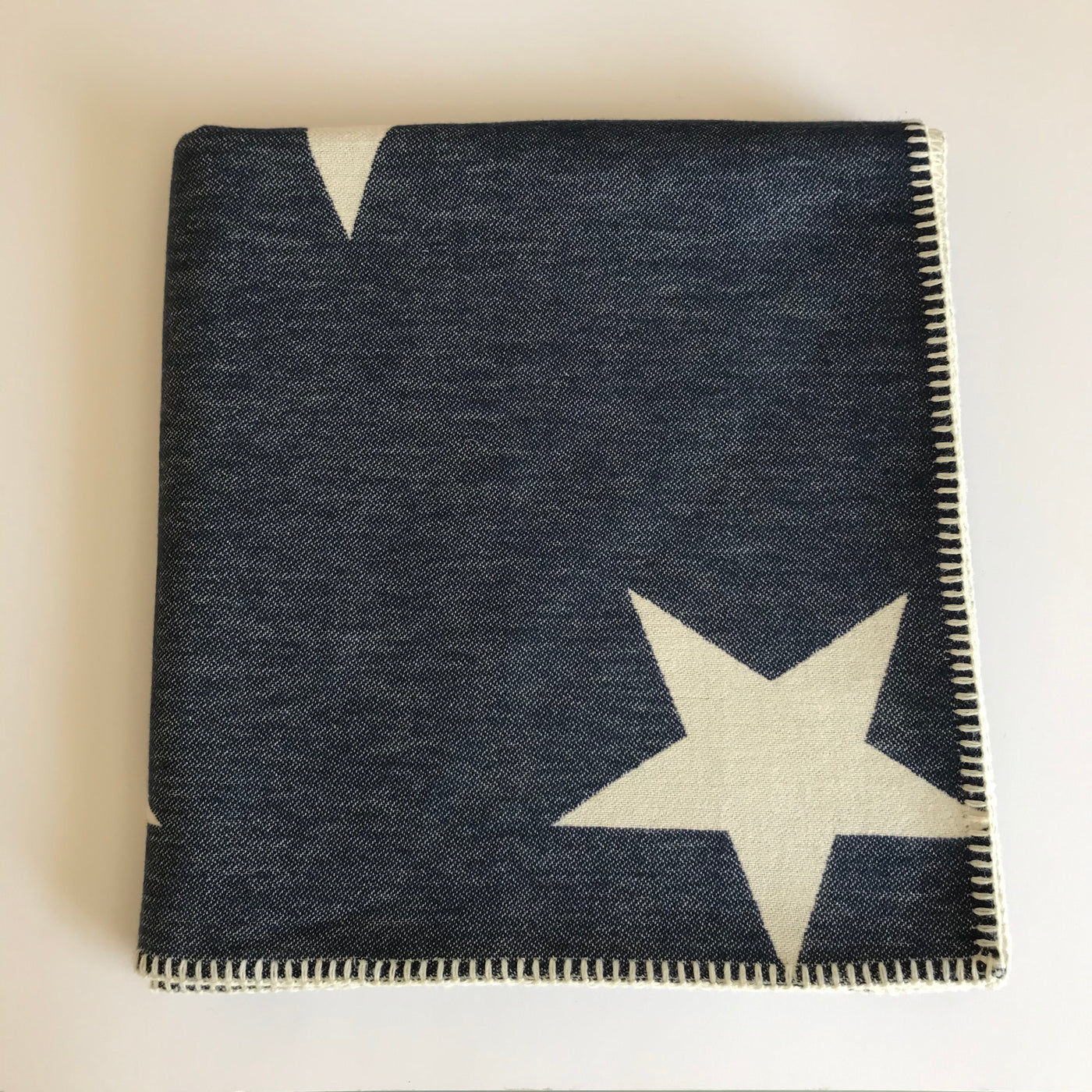 Rory & Ruby reversible star design throw in navy and ivory with traditional blanket stitch edging.