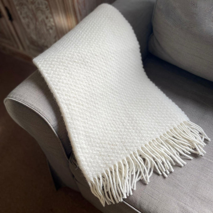 St Andrews Hamper Company luxurious pure new wool armchair throw in ivory with contemporary wafer pattern and self coloured twisted tassel fringing. Perfect as a soft and cosy shoulder wrap for snuggling into, as a stylish knee rug or the finishing touch to a bed, sofa or armchair.
