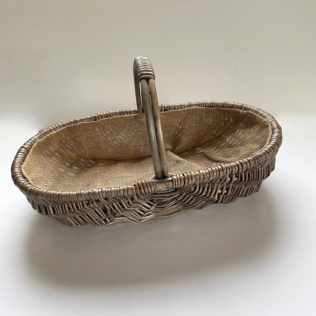 Oval shaped traditional woven basket with hessian lining and handle.